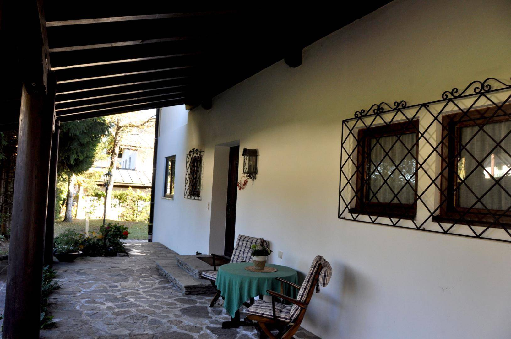 Überdachte Terrasse mit rustikalen Gartenmöbeln und Steinboden, ideal für entspannte Stunden.