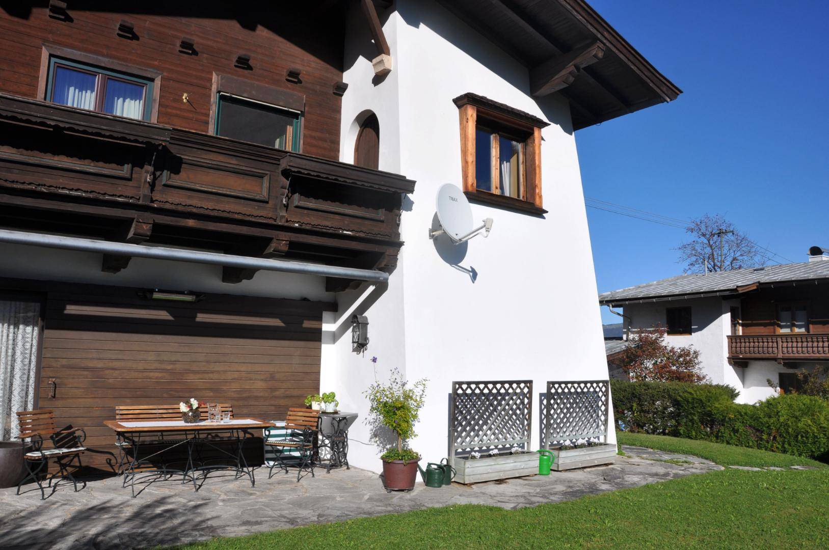 Sonniger Terrassenbereich mit Gartenmöbeln und Zugang zum Balkon im traditionellen Stil.