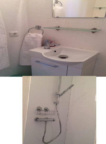 Badezimmerdetails mit modernem Waschbecken, Spiegel und einer Duscharmatur.