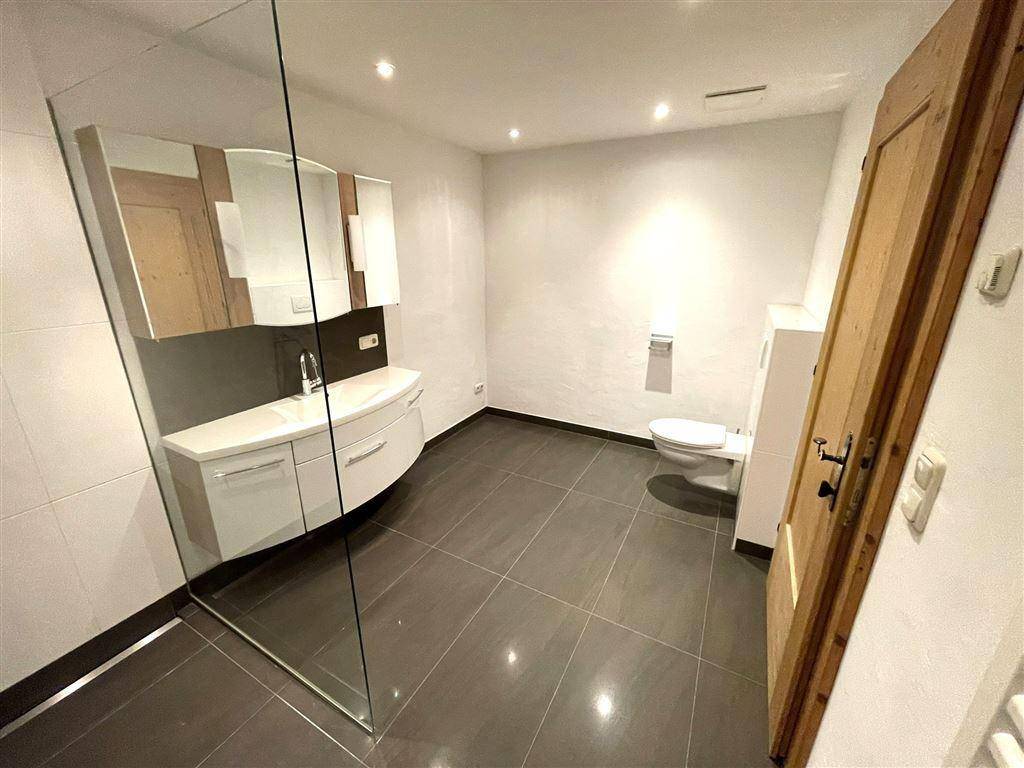 Helles Badezimmer mit moderner Ausstattung, großem Spiegel und begehbarer Dusche.