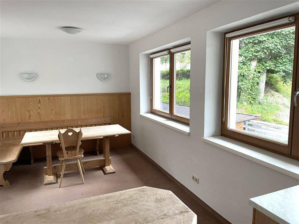 Traditioneller Essbereich mit Holztisch und Bänken, umgeben von Holzvertäfelung und Fenstern.