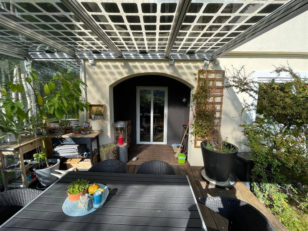 Überdachte Terrasse mit Essbereich und Pflanzen, ideal für entspannte Stunden im Freien.