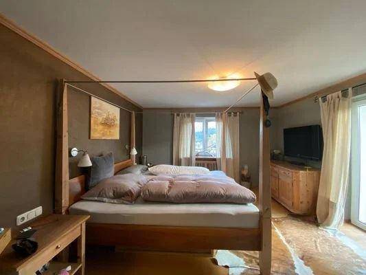 Gemütliches Schlafzimmer mit Himmelbett, Holzelementen und Zugang zu einem Balkon.
