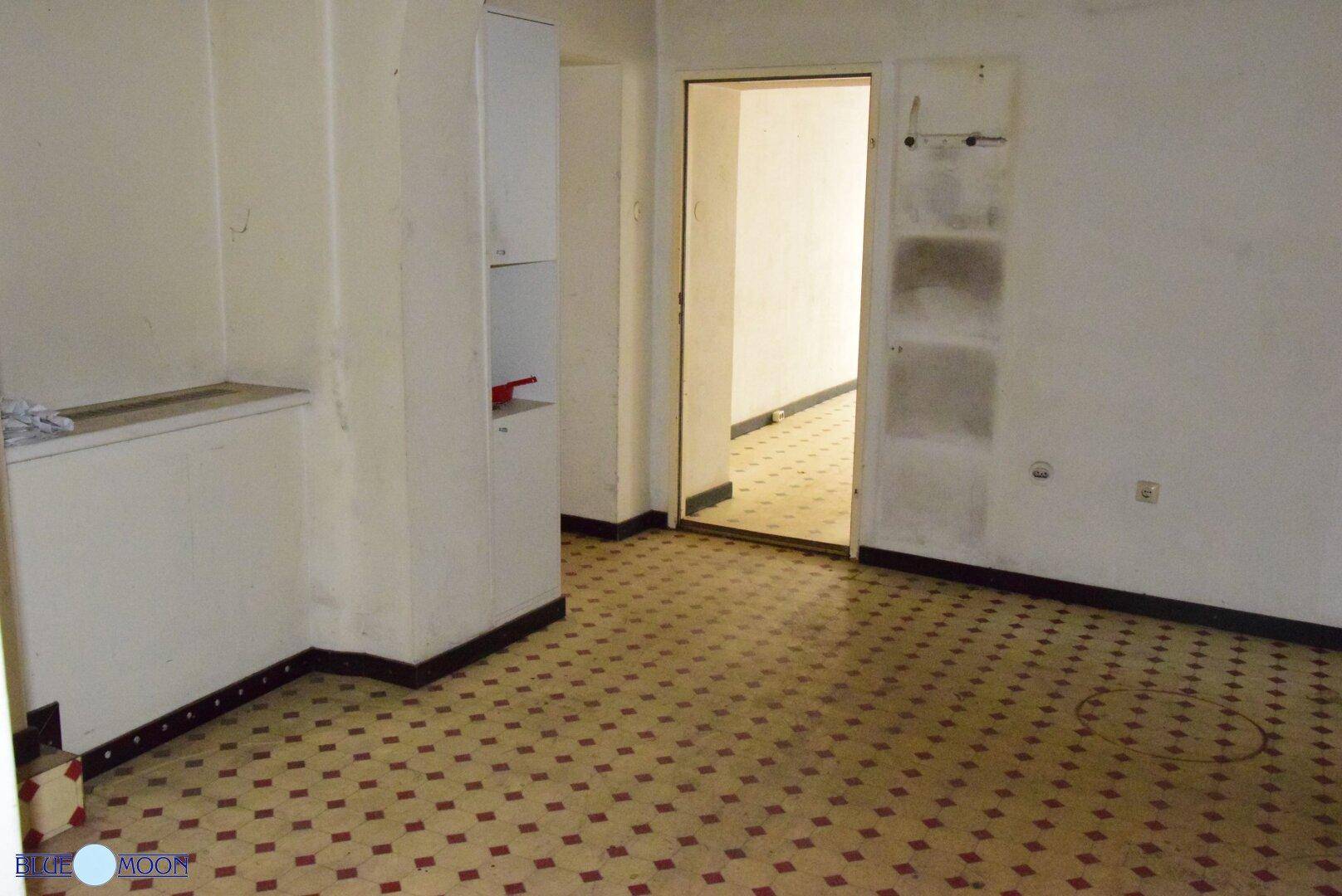 Raum mit gemustertem Fliesenboden, weißen Wänden und einem Einbauschrank, der auf frühere Nutzung hinweist.