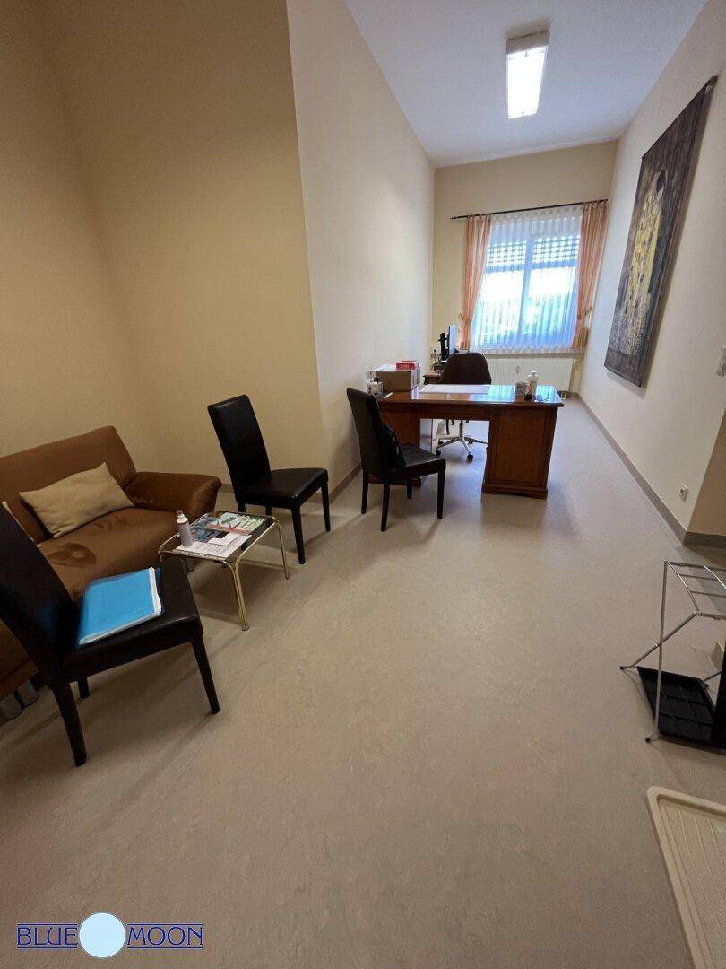 Helles Büro mit Holzschreibtisch, beigen Wänden und einem Fenster mit Vorhängen.