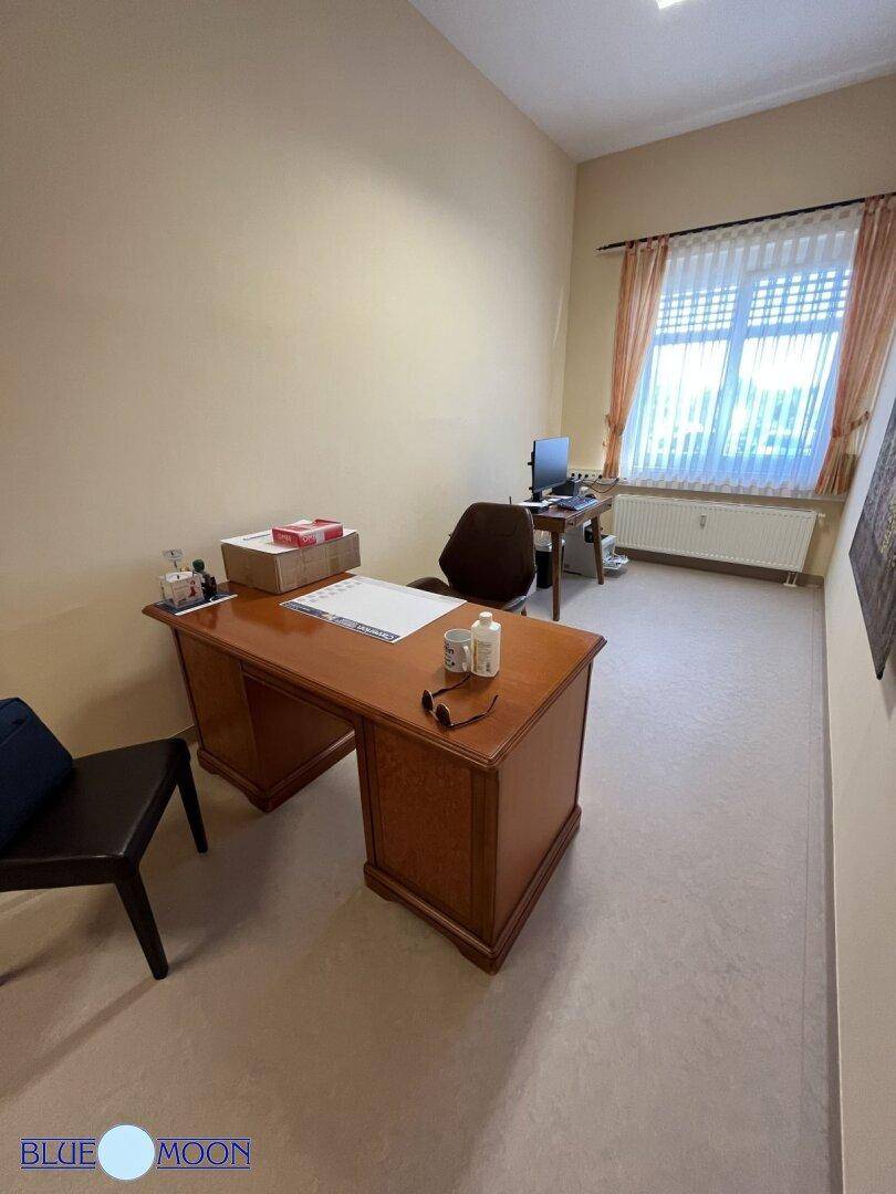 Schlichtes Büro mit einem großen Holzschreibtisch und einem Fenster mit Blick nach draußen.