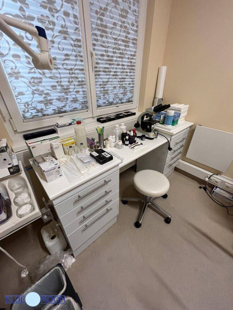 Arbeitsbereich in einem Untersuchungsraum mit Schränken, Mikroskop und Fenster.