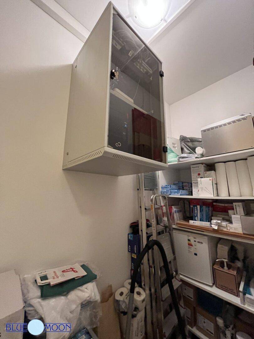 Lagerraum mit einem Serverschrank, Regalen und verschiedenen medizinischen Materialien.
