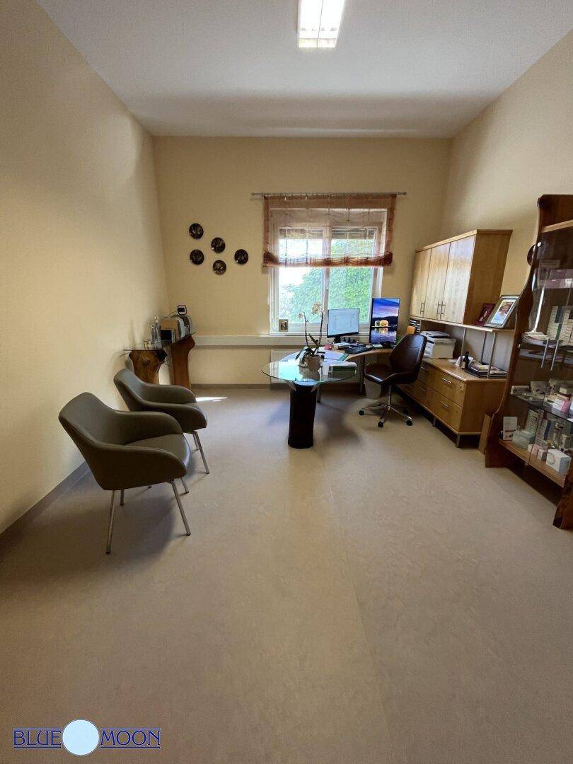 Geräumiges Büro mit mehreren Sitzgelegenheiten, einem Schreibtisch und einem großen Fenster.