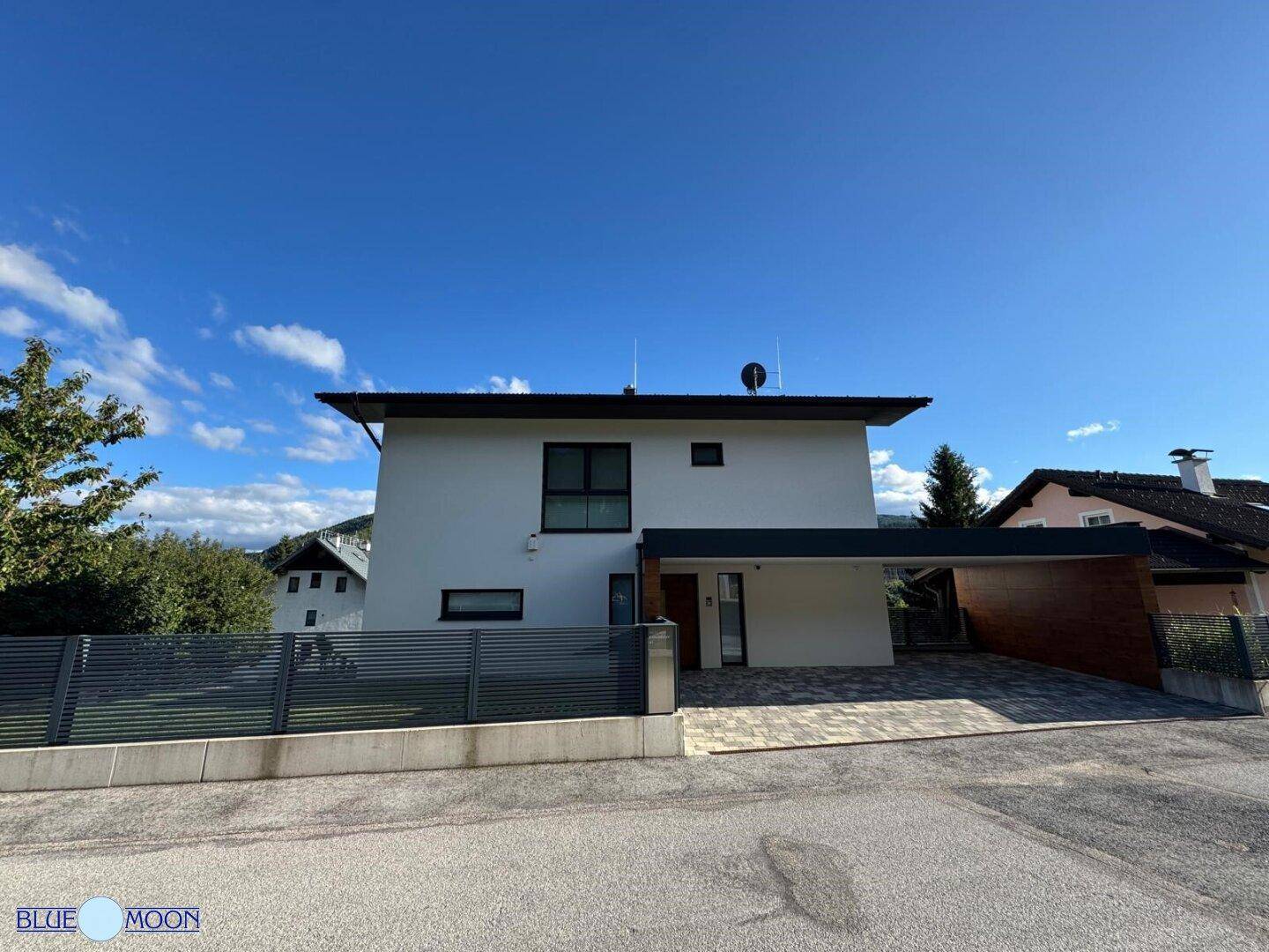 Weitläufige Ansicht des modernen Einfamilienhauses mit Carport und gepflegtem Vorgarten.
