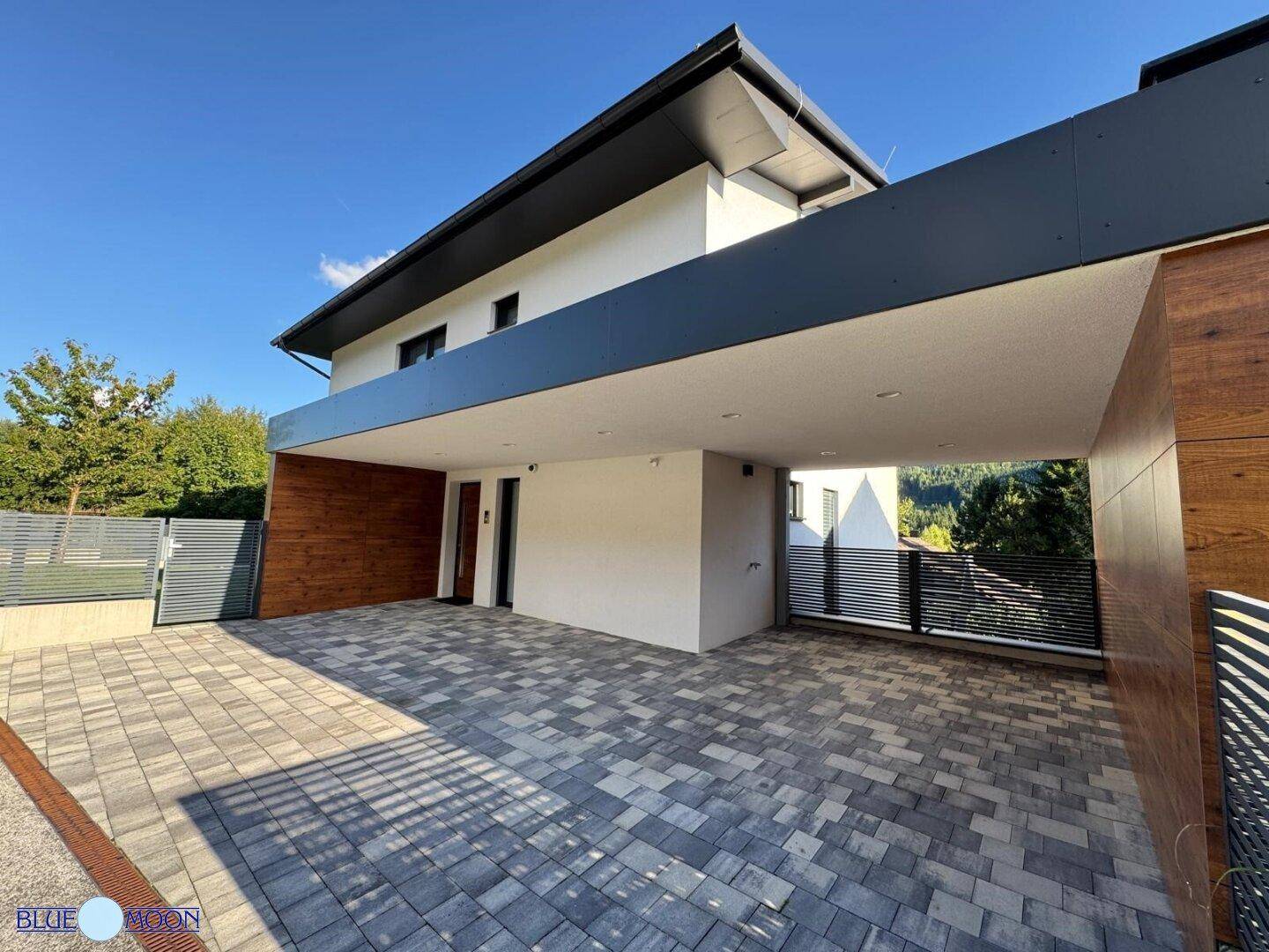 Geräumiger Carport-Bereich mit moderner Pflasterung und Zugang zum Hauseingang.