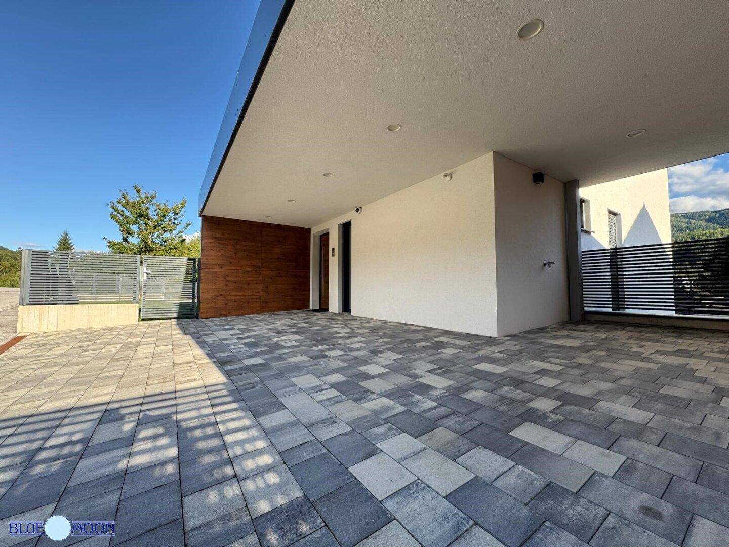 Heller und geräumiger Carport-Bereich mit moderner Pflasterung und indirekter Beleuchtung.