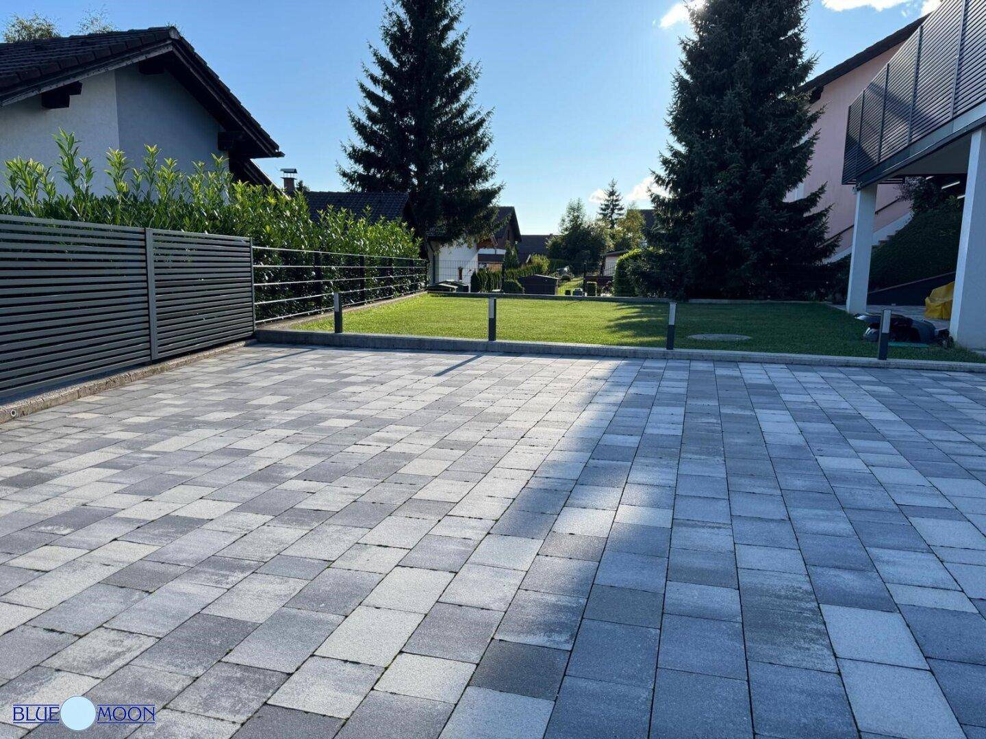 Weitläufige Auffahrt mit moderner Pflasterung und integrierter Außenbeleuchtung.