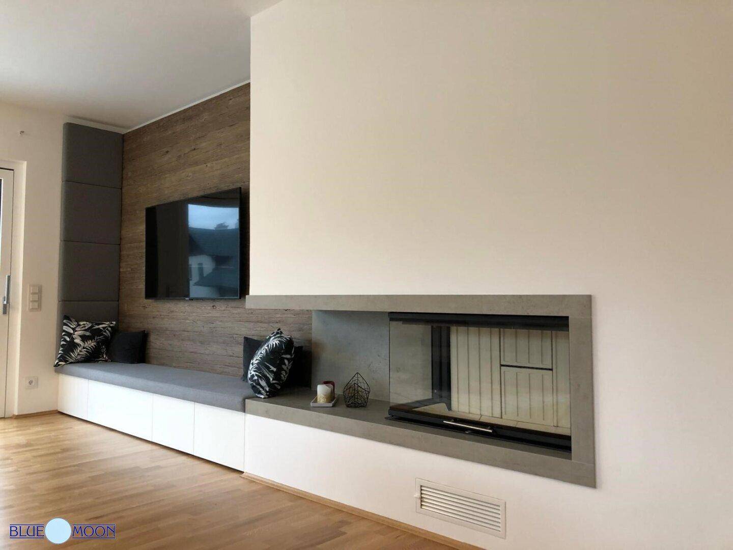 Modernes Wohnzimmer mit integriertem Kamin, Holzwand und Sitzbank.
