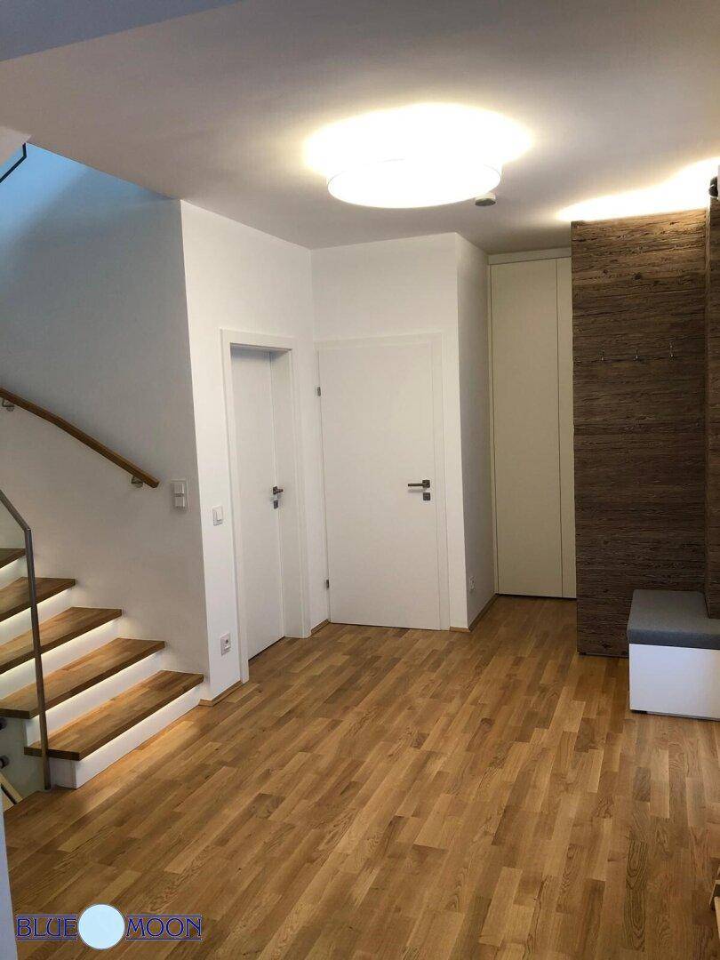 Heller Eingangsbereich mit Holzparkettboden, Garderobe und Treppenaufgang.