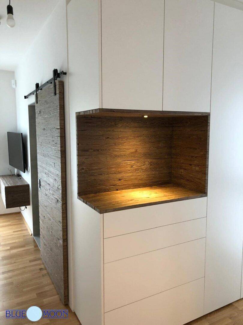 Schlafzimmer mit integrierten Schränken, Holzelementen und Schiebetür zum Bad.