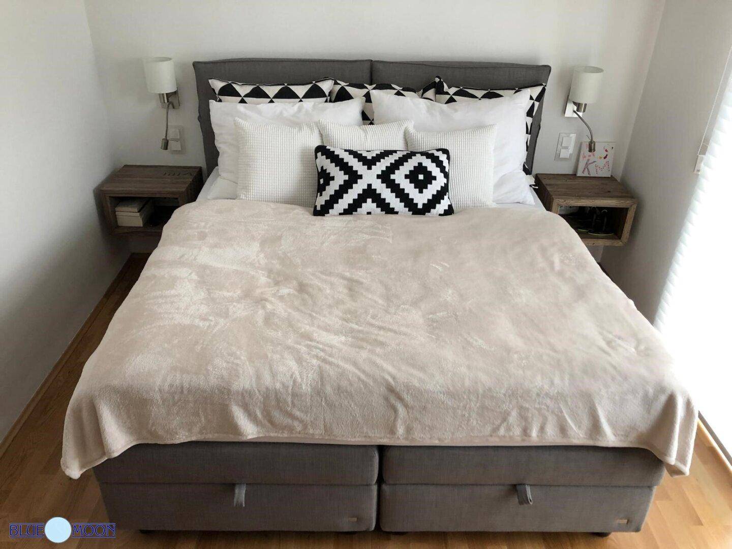 Gemütliches Schlafzimmer mit Doppelbett, Nachttischen und modernen Kissen.