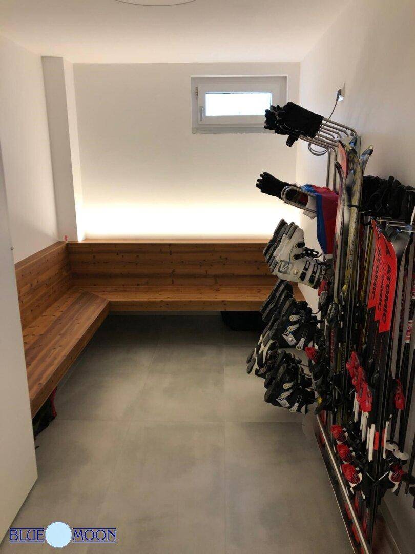 Praktischer Skiraum mit Holzbänken und Halterungen für Skiausrüstung.