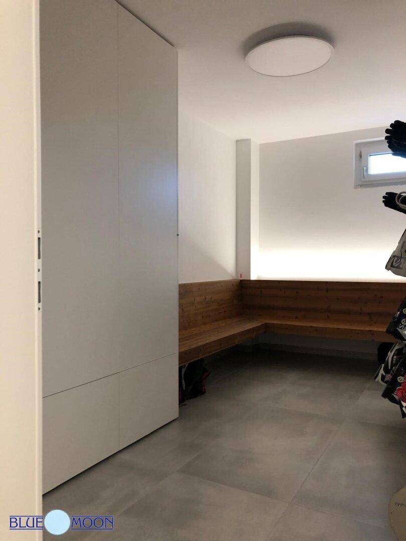 Funktionaler Abstellraum mit integrierten Schränken und Sitzgelegenheiten aus Holz.