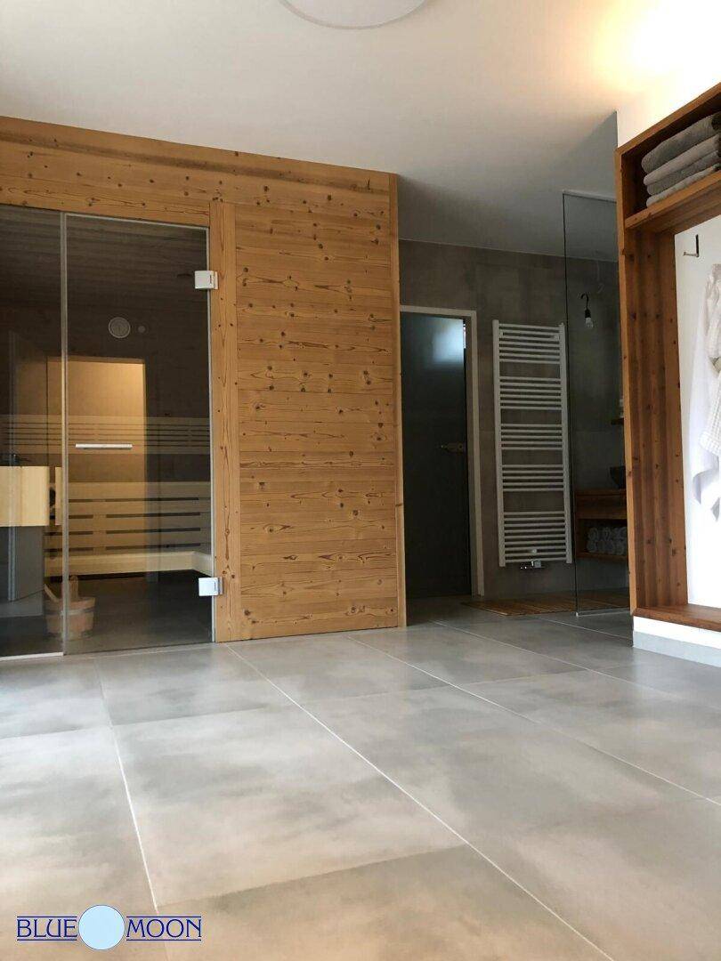 Moderner Wellnessbereich mit Sauna und Zugang zu einer begehbaren Dusche.