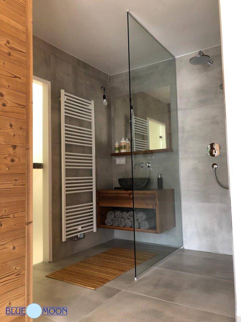 Elegantes Badezimmer mit begehbarer Dusche, Holzwaschtisch und grauen Fliesen.