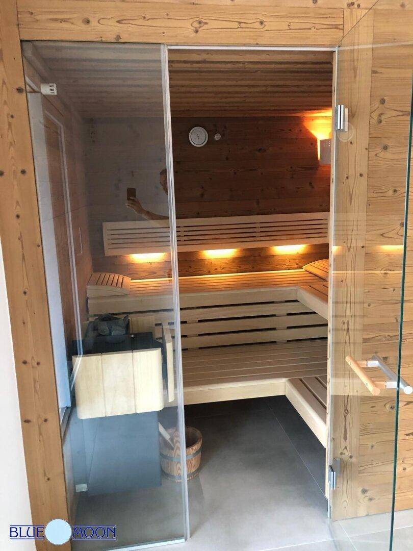 Geräumige Holzsauna mit mehreren Bänken und indirekter Beleuchtung für Entspannung.