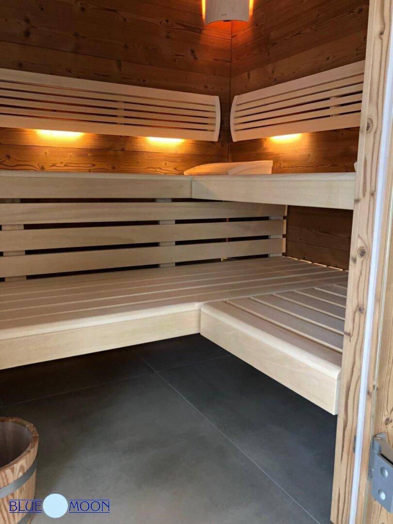 Detailansicht der Holzsauna mit breiten Bänken und dunklem Fliesenboden.