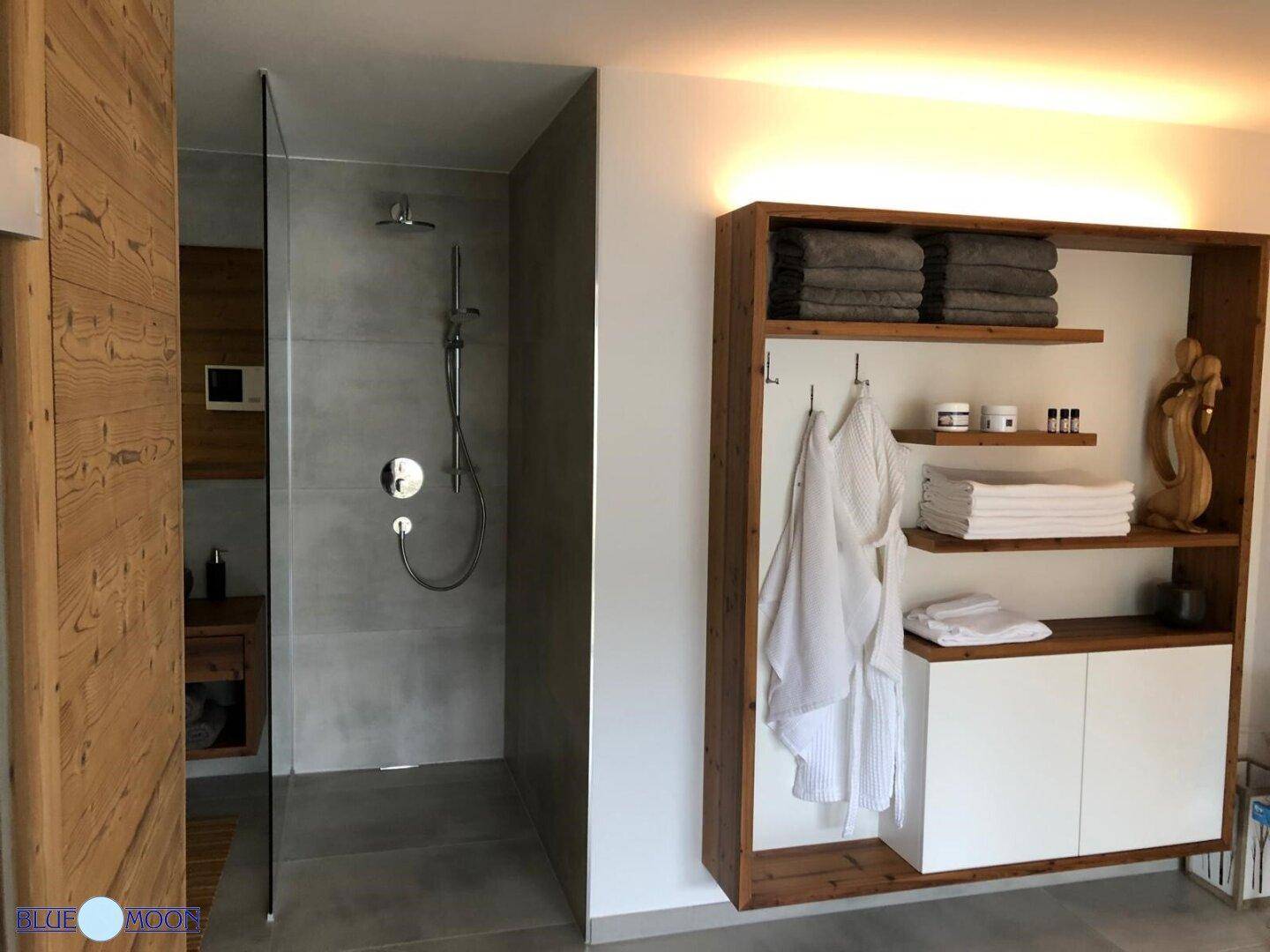 Modernes Badezimmer mit begehbarer Dusche und offenem Holzregal für Handtücher.