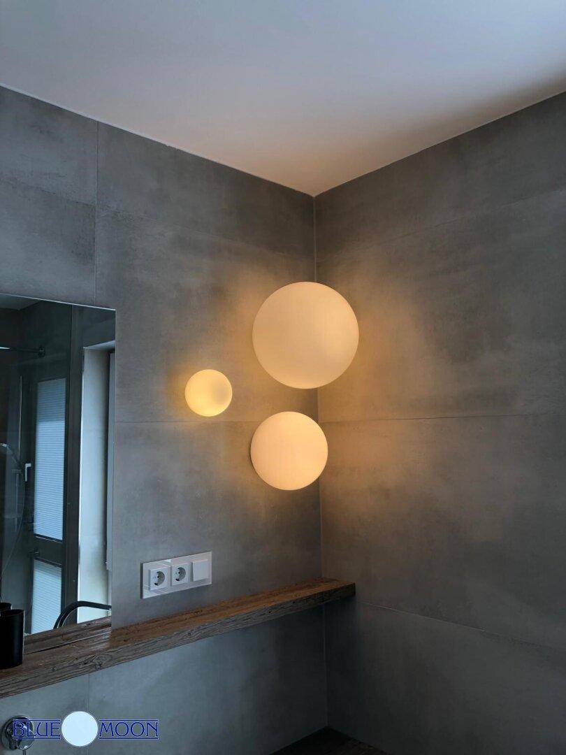 Detailansicht der modernen Wandbeleuchtung und grauen Fliesen im Badezimmer.