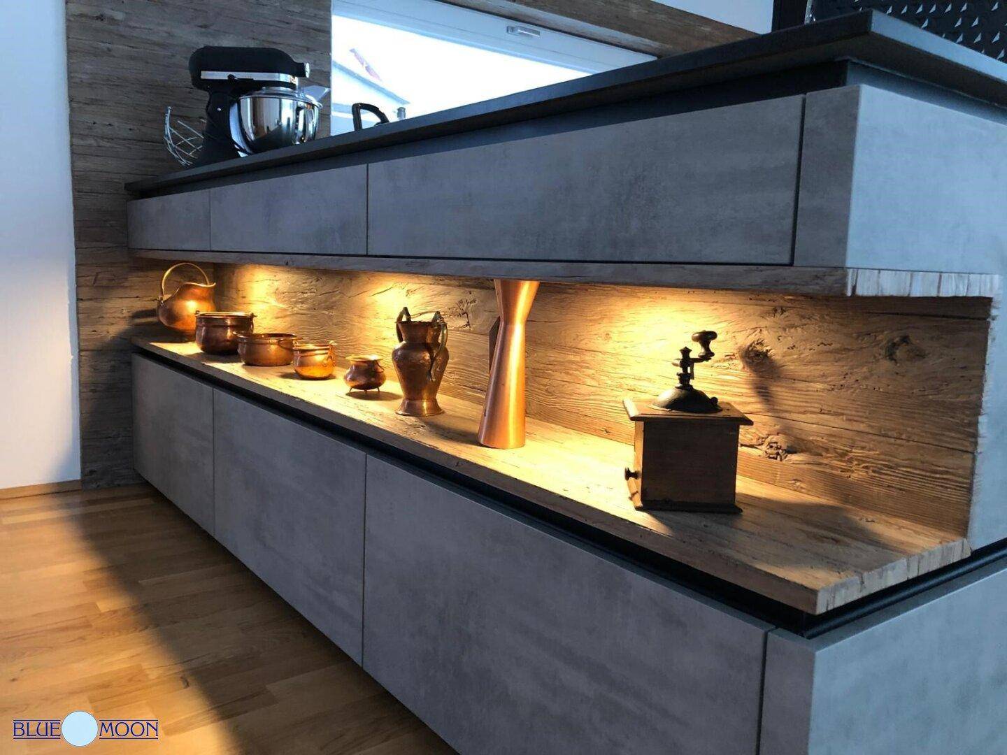 Moderne Küchenzeile mit grauen Unterschränken, Holzdetails und indirekter Beleuchtung.