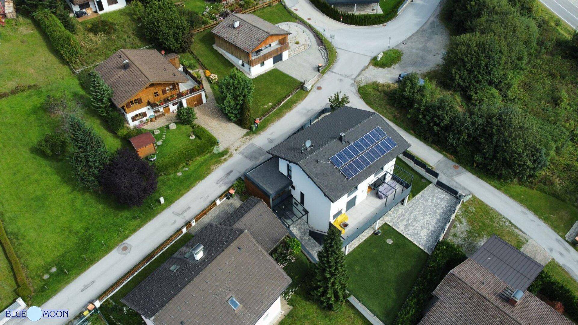 Luftaufnahme eines modernen Hauses mit Solaranlage auf dem Dach in ländlicher Umgebung.