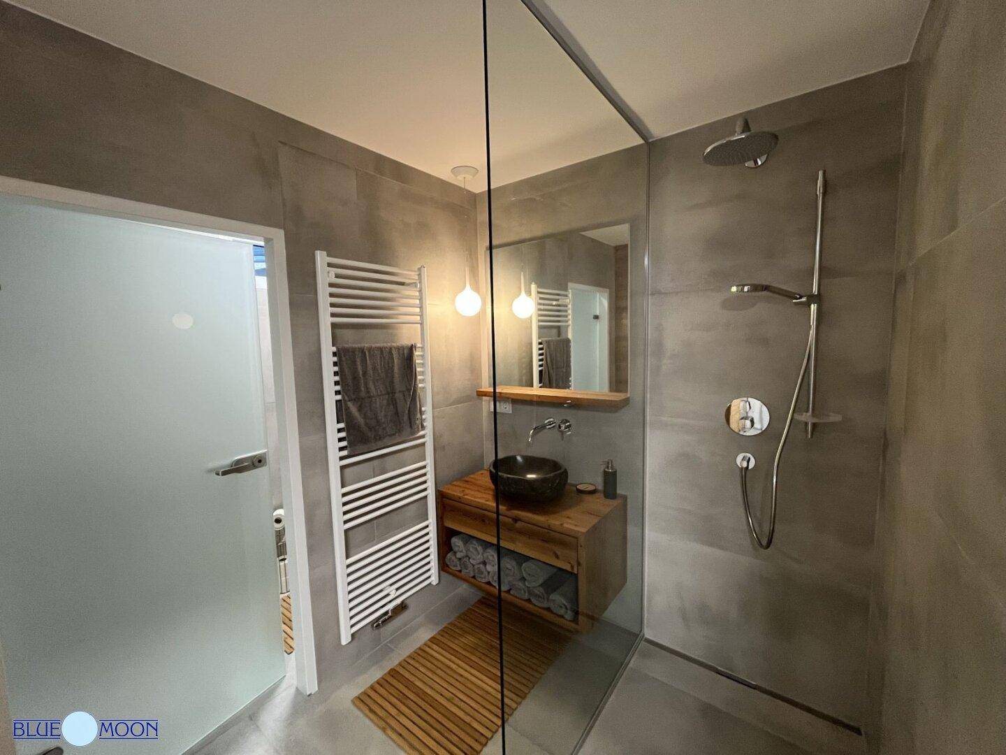 Geräumiges Badezimmer mit begehbarer Dusche, Holzwaschtisch und Heizkörper.
