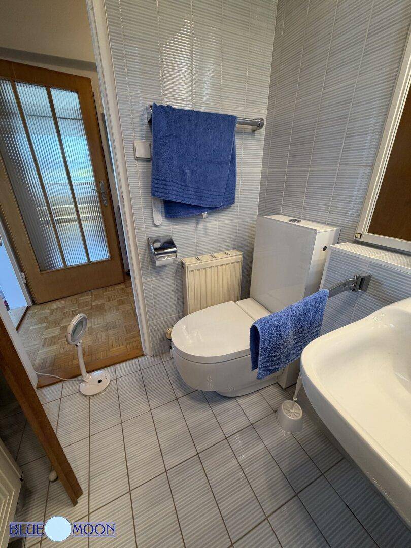Badezimmer mit Toilette, Waschbecken und hellen Fliesen, die eine saubere und funktionale Umgebung schaffen.