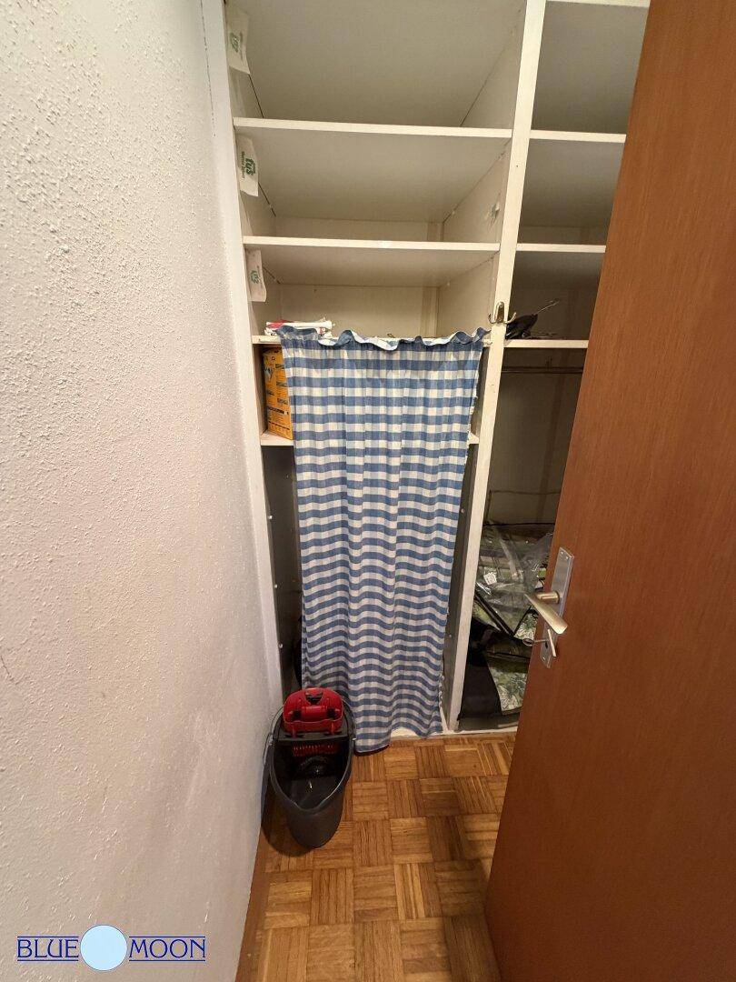 Praktischer Abstellraum mit Regalen und einem karierten Vorhang, ideal zur Organisation von Gegenständen.