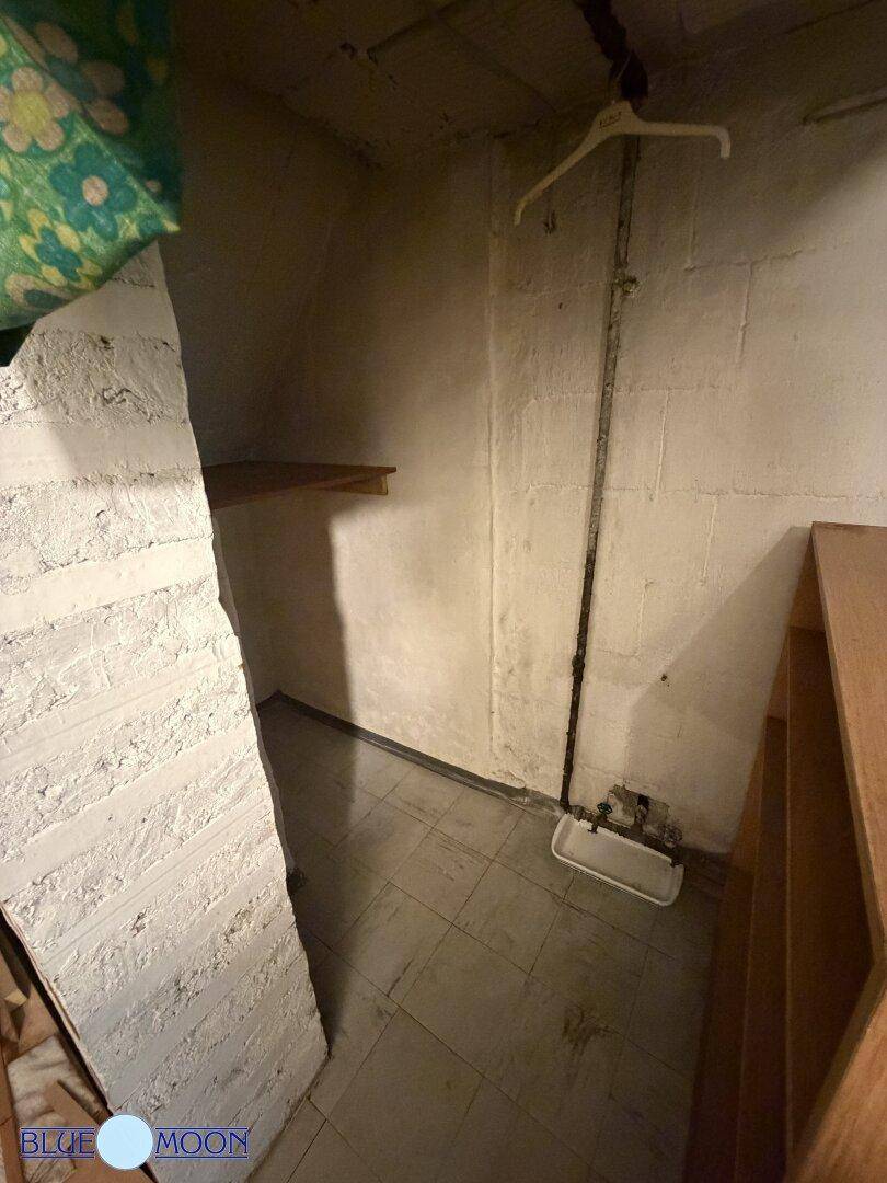 Einfacher Kellerraum mit Betonwänden und kleinem Waschbecken, ideal als Abstellfläche.