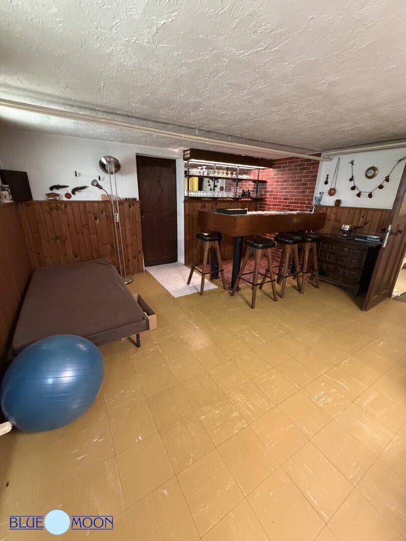 Gemütlicher Kellerraum mit einer Bar, Hockern und Holzvertäfelung, ideal für gesellige Abende.