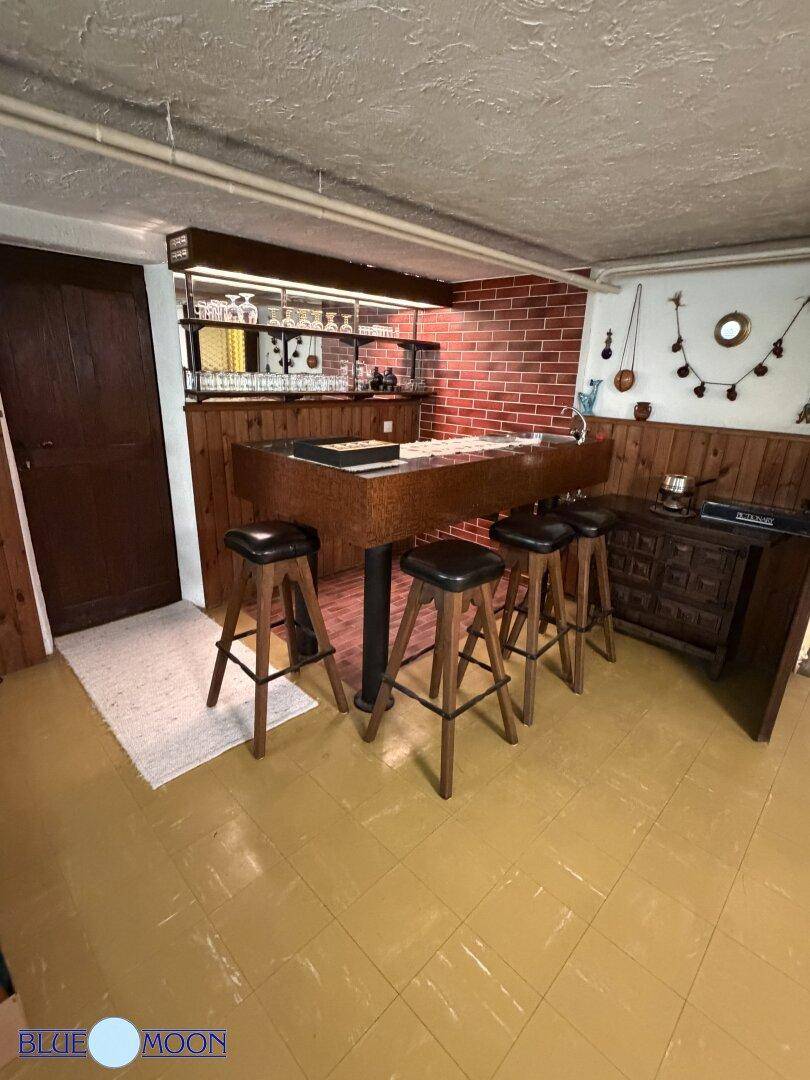 Detailansicht der rustikalen Bar im Keller mit Backsteinwand und bequemen Barhockern.