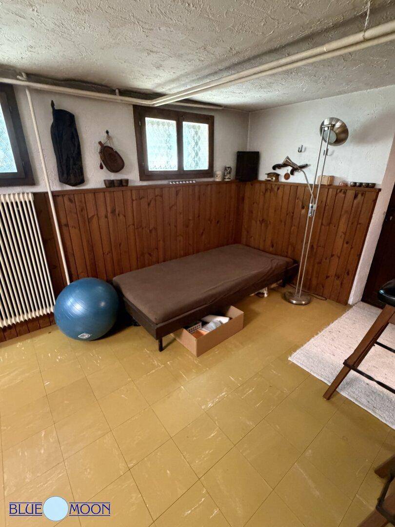 Heller Kellerraum mit einem Bett, Holzvertäfelung und einem Fenster, das Tageslicht hereinlässt.