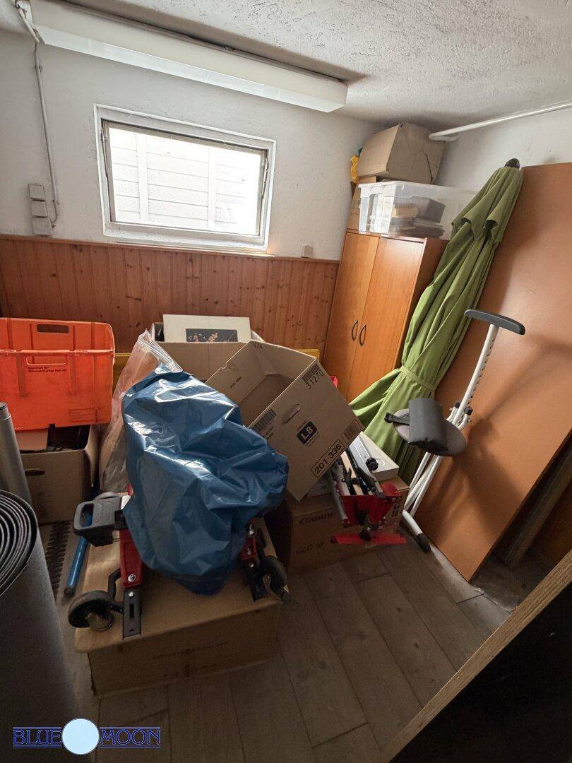 Geräumiger Abstellraum im Keller mit Fenster, gefüllt mit verschiedenen Lagergegenständen und Kartons.