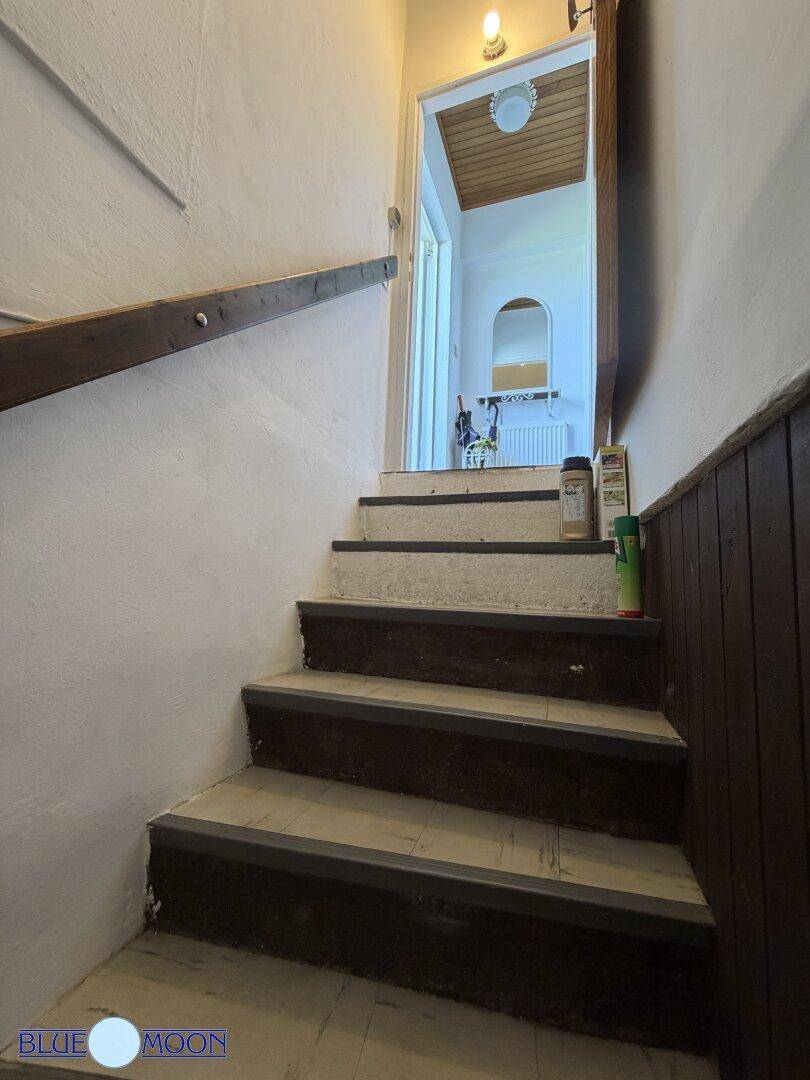 Treppenaufgang vom Kellergeschoss mit Holzvertäfelung an der Wand, der in den oberen Bereich führt.