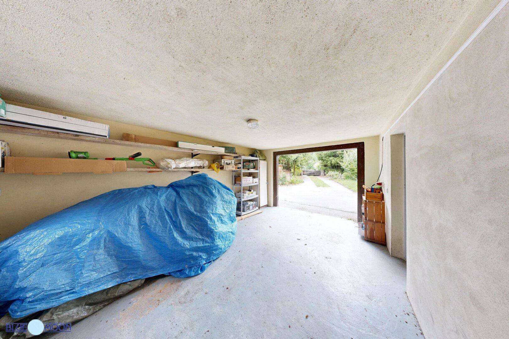 Geräumige Garage mit Betonboden und Regalen für Lagerung und Werkzeuge.