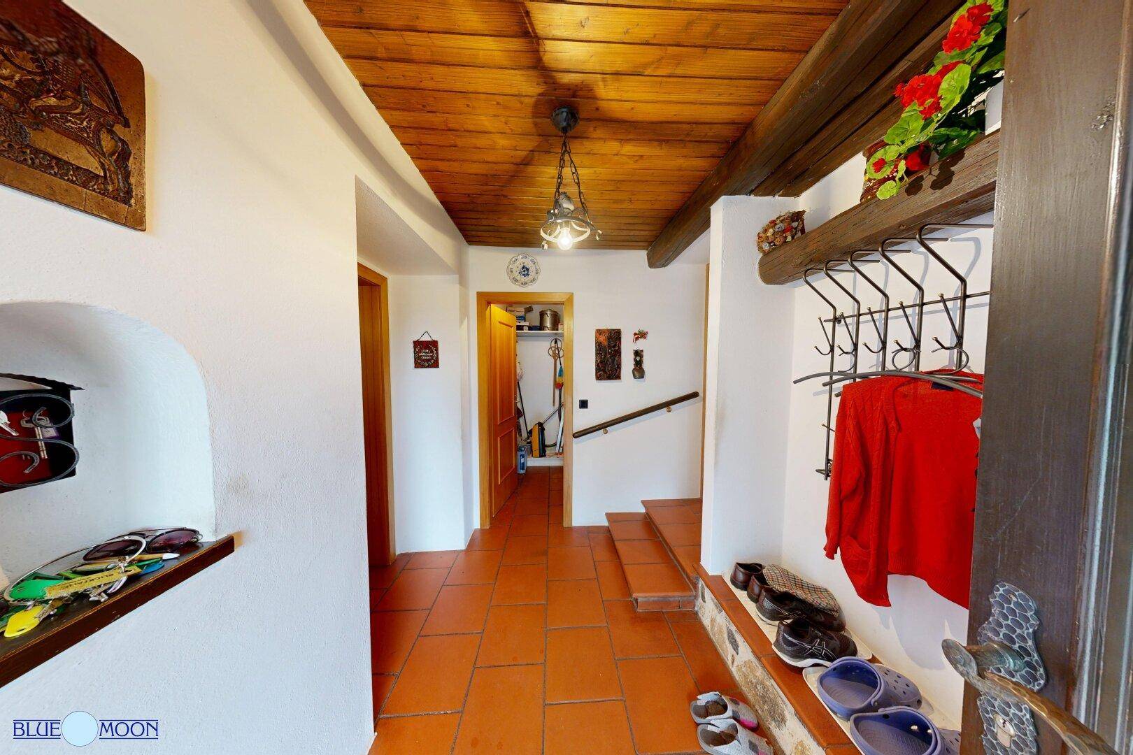 Gemütlicher Eingangsbereich mit Holzdecke, Terrakottafliesen und traditioneller Garderobe.