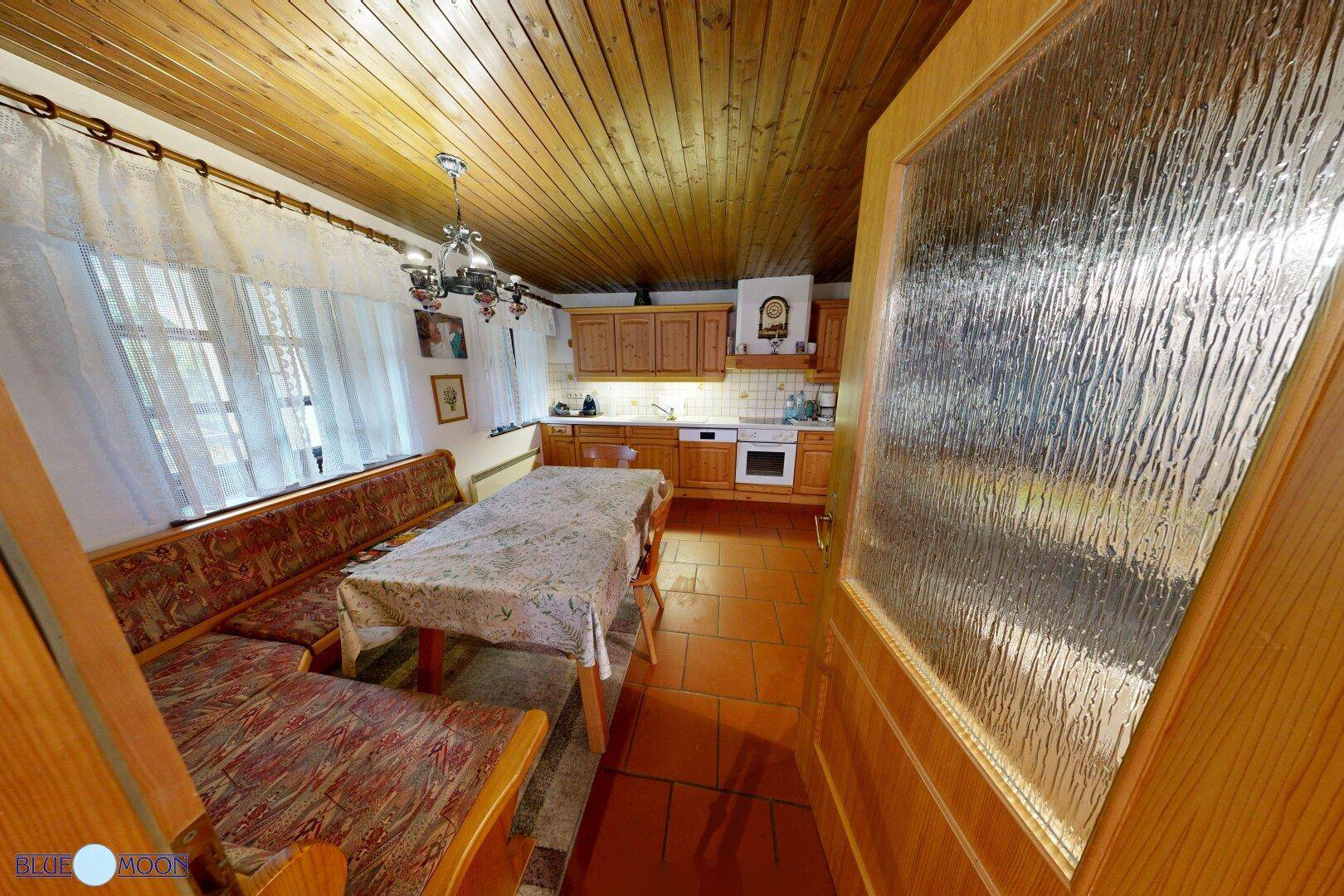 Traditionelle Wohnküche mit Holzmöbeln, Terrakottafliesen und einem Esstisch mit Eckbank.