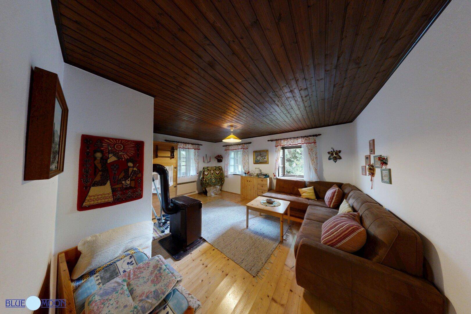 Gemütliches Wohnzimmer mit Holzdielenboden, Holzdecke und einem Kaminofen für warme Abende.