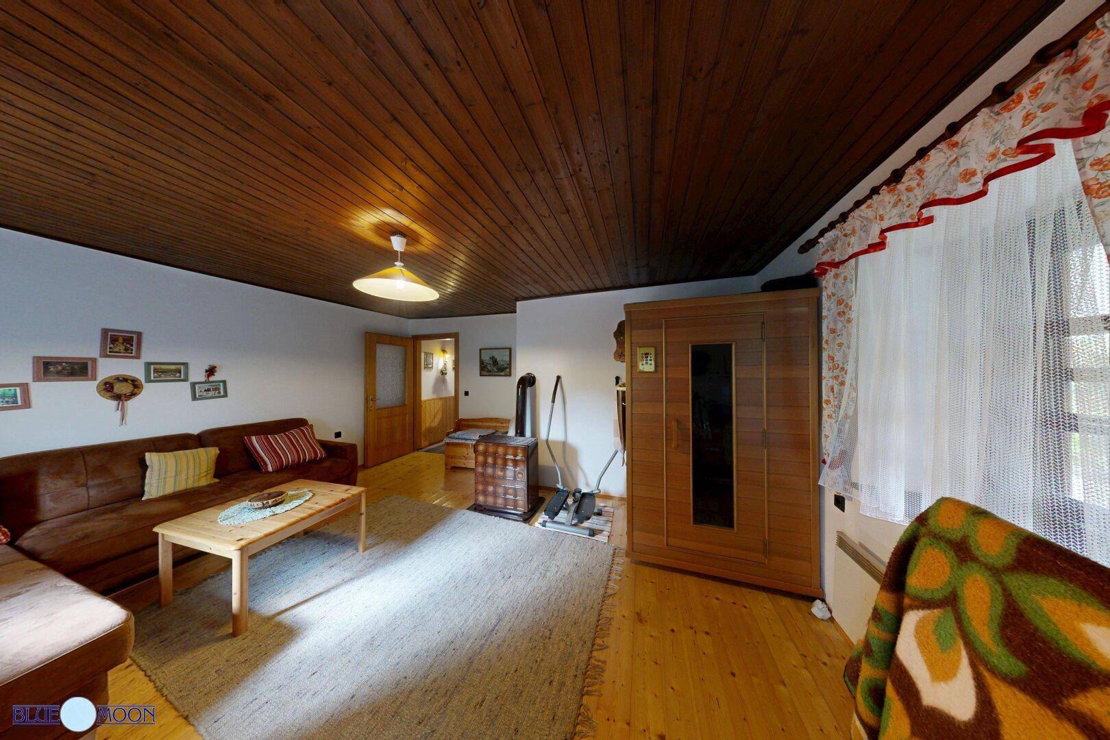 Rustikales Wohnzimmer mit Holzboden, Kaminofen und einer kleinen Sauna für entspannte Stunden.