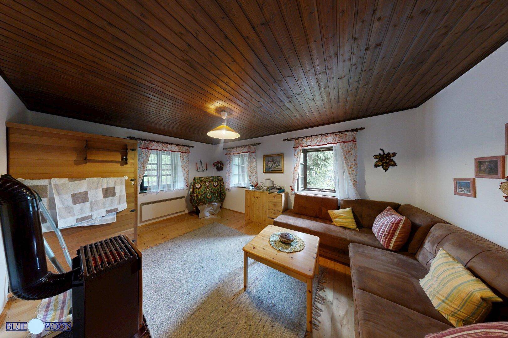 Helles Wohnzimmer mit Holzbalkendecke, Kaminofen und gemütlicher Sitzecke im traditionellen Stil.