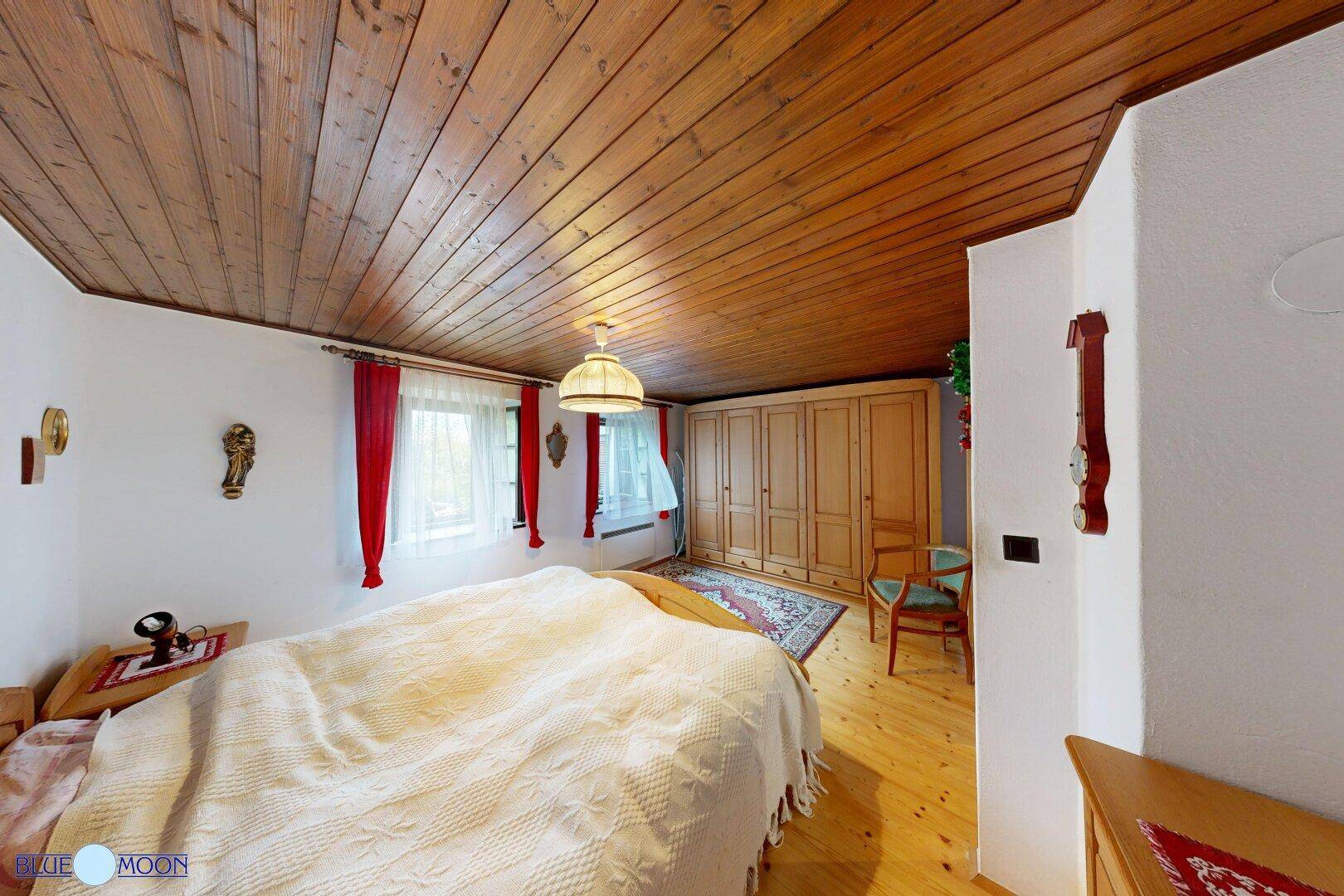 Geräumiges Schlafzimmer mit Holzboden, Holzbalkendecke und einem großen Kleiderschrank.