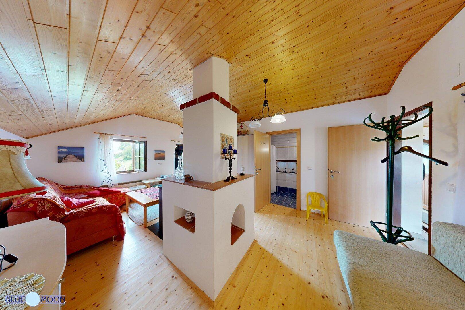 Offener Wohn- und Essbereich im Dachgeschoss mit Holzbalkendecke und Kamin.