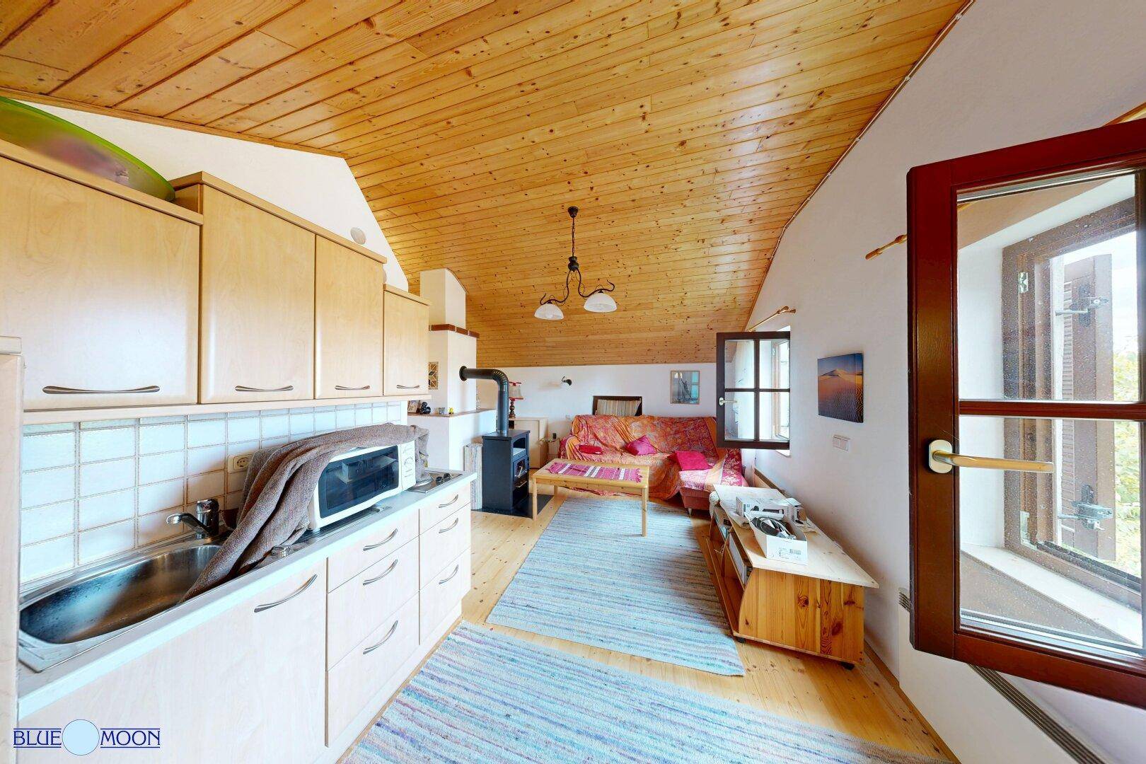 Dachgeschosswohnung mit offener Küchenzeile, Wohnbereich und Holzbalkendecke.