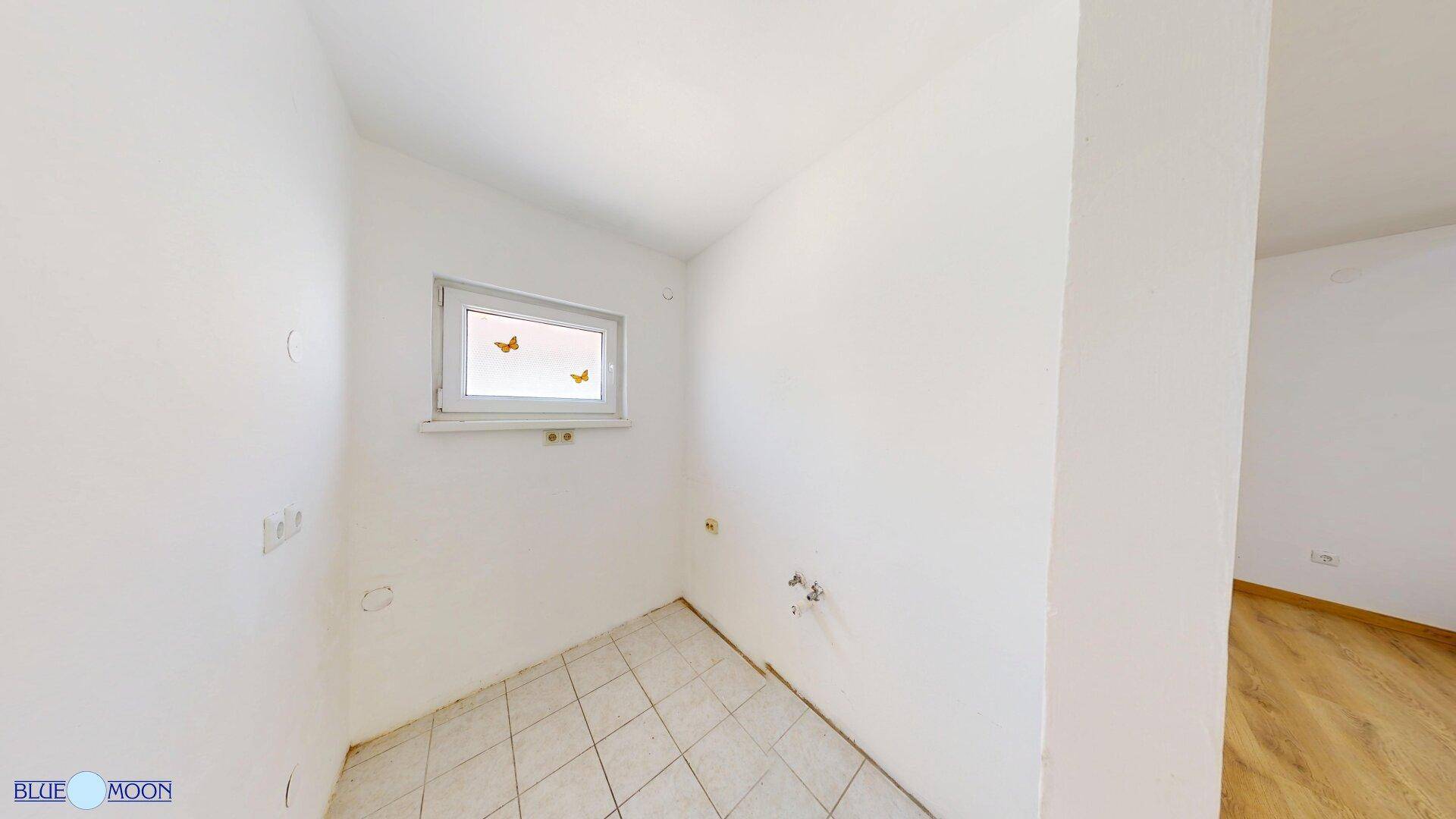 Kleiner Raum mit Fliesenboden, Fenster und Anschlüssen für Wasser.